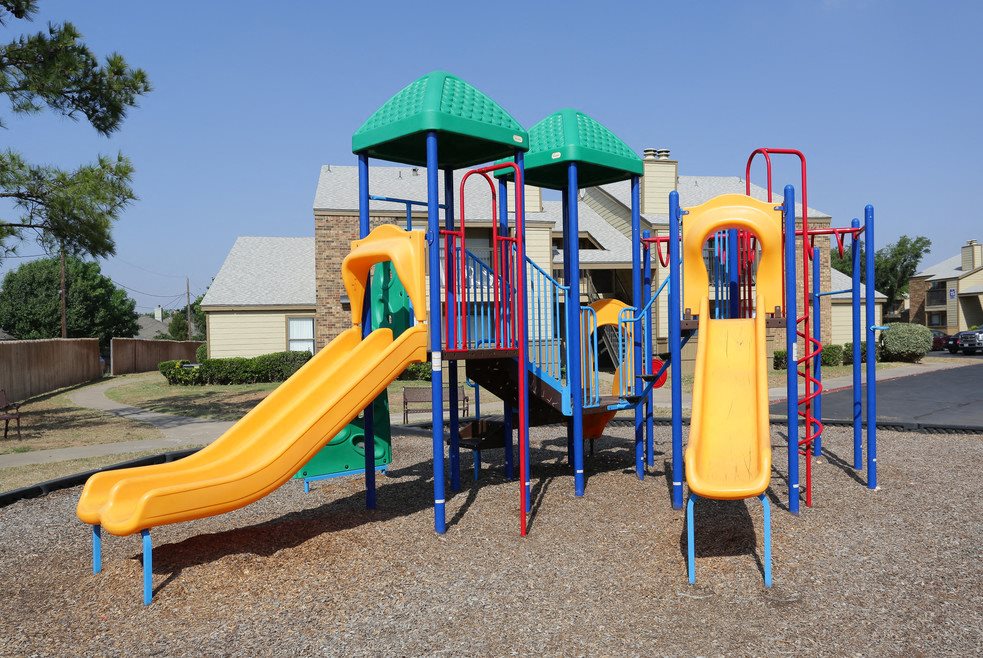 A playground with a yellow slide and a green roof.